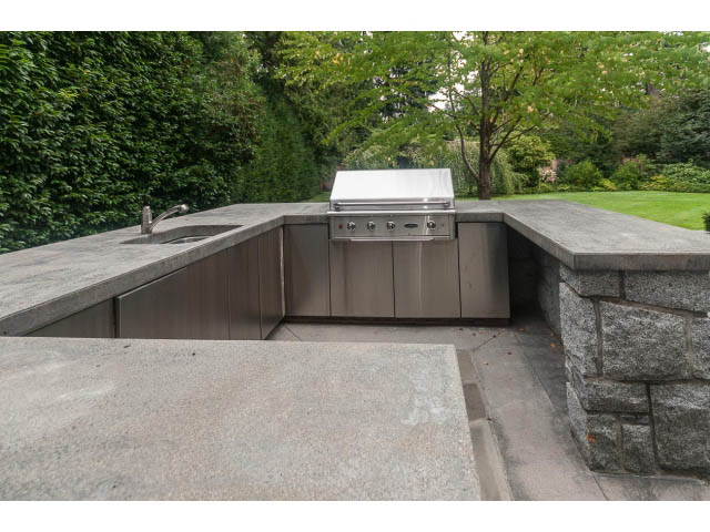 Bright outdoor kitchen with granite countertops and built-in grill, surrounded by lush greenery. - 5630 Angus Dr., Vancouver West Side