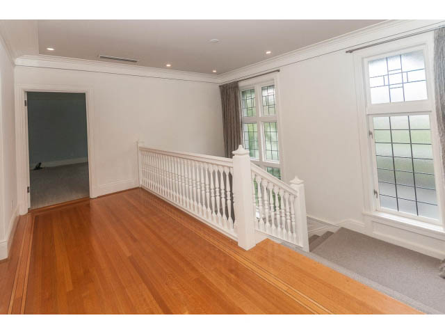 Bright living room with hardwood floors and large windows, leading to a staircase. - 5630 Angus Dr., Vancouver West Side