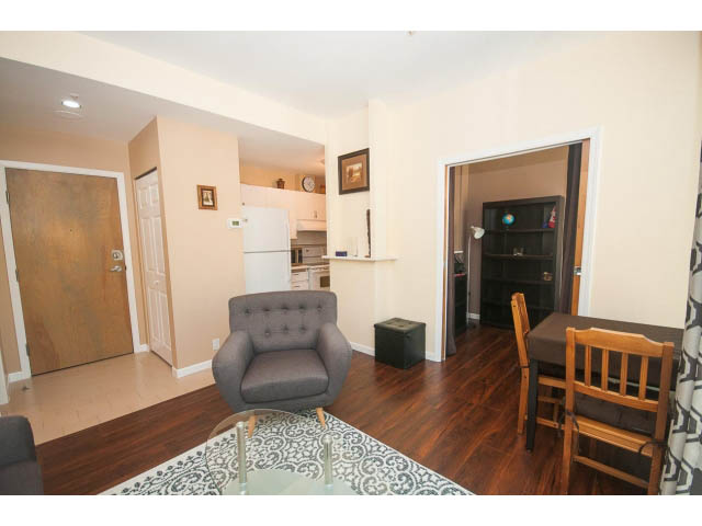 Furnished living room with hardwood floors, cozy seating, and a kitchen in the background. - 1213 - 989 Nelson, Vancouver Downtown