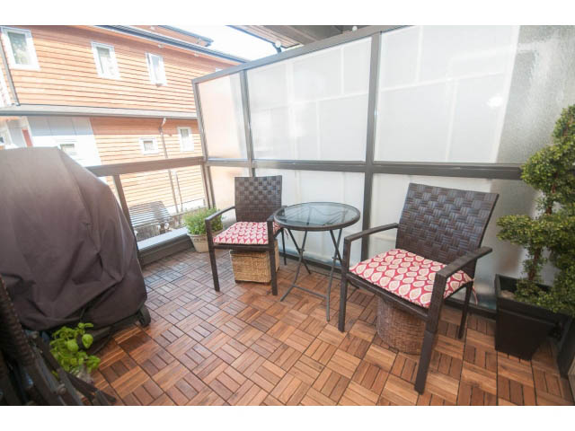 Furnished patio with wooden flooring, wicker furniture, and a sliding glass wall. - 205 - 116 West 23rd, North Vancouver