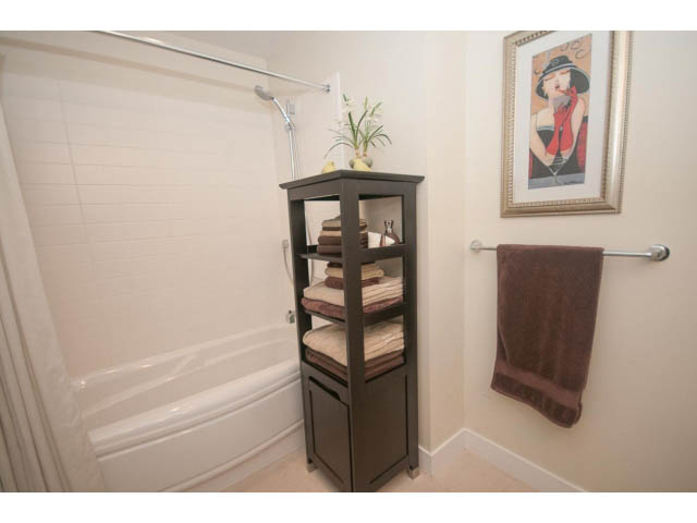 Furnished bathroom with a dark wooden shelf, neatly folded towels, and a framed artwork. - 205 - 116 West 23rd, North Vancouver
