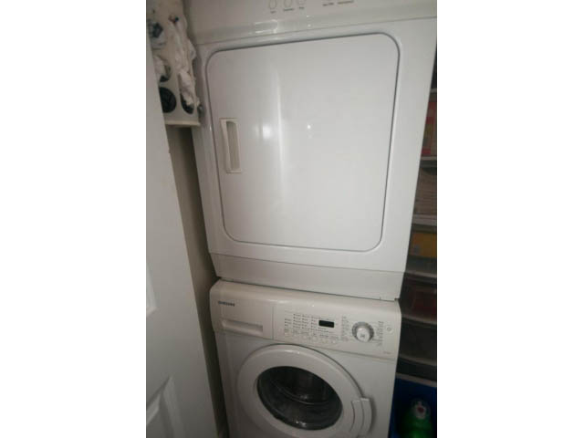Bright laundry room with stacked washer and dryer, white appliances. - 205 - 116 West 23rd, North Vancouver