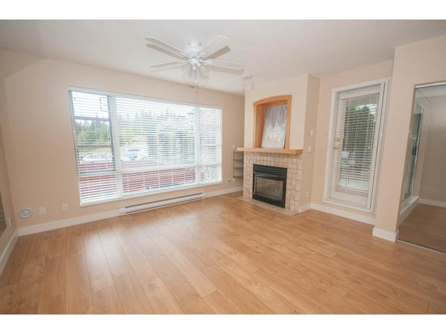 Bright living room with hardwood floors, city view, and fireplace. - 202 - 3629 Deercrest, North Vancouver