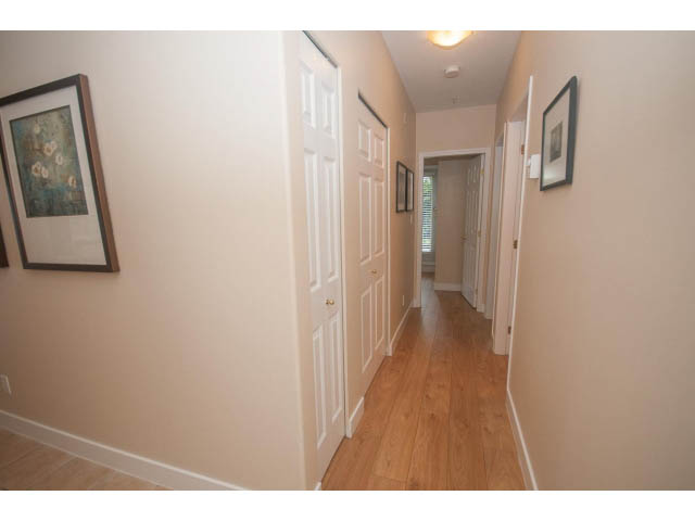Furnished hallway with hardwood floors and framed artwork. - 202 - 3629 Deercrest, North Vancouver