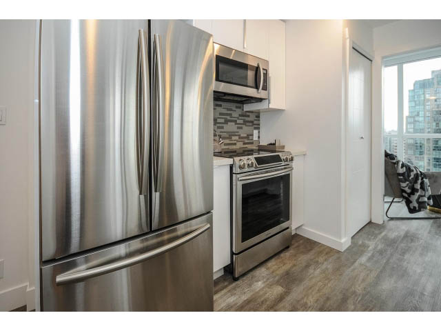 Bright kitchen with stainless steel appliances, hardwood floors, and a city view. - 2102 - 1199 Seymour Street, Vancouver Downtown