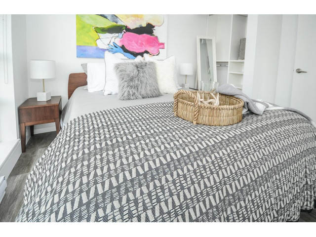 Bright bedroom with patterned bedding, modern artwork, and wooden nightstands. - 2102 - 1199 Seymour Street, Vancouver Downtown