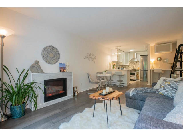 Furnished living room with hardwood floors, cozy fireplace, and modern decor. - 306 - 570 E 8th Avenue, Vancouver East Side