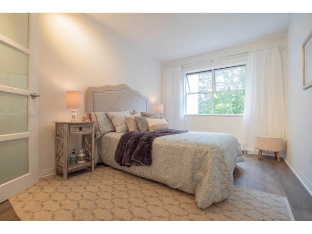 Furnished 1-bedroom + den with cozy bed, patterned carpet, and large window with view. - 306 - 570 E 8th Avenue, Vancouver East Side