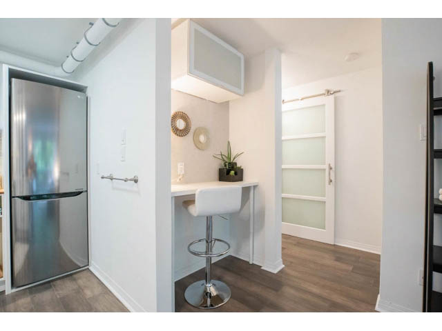 Bright kitchen with white countertops, hardwood floors, and a modern bar stool. - 306 - 570 E 8th Avenue, Vancouver East Side
