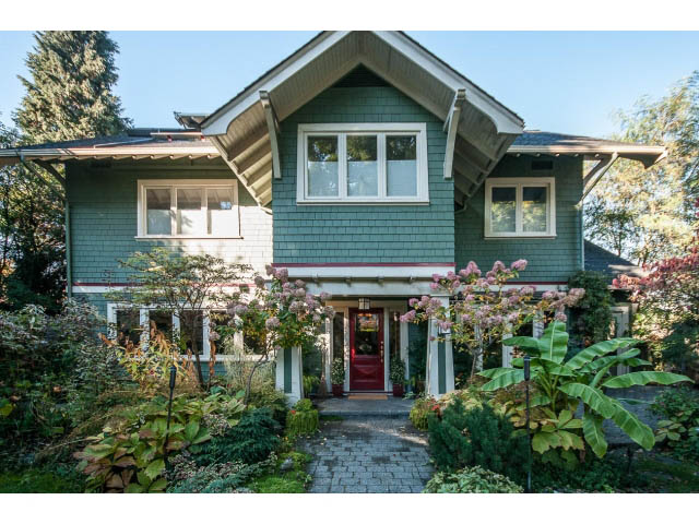 Furnished 3-bedroom house with green siding and a red front door, surrounded by lush greenery. - 1015 West 16th Ave, Vancouver West Side