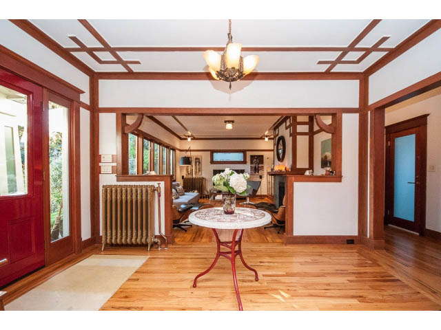 Spacious living room with hardwood floors, exposed beams, and a vintage chandelier. - 1015 West 16th Ave, Vancouver West Side