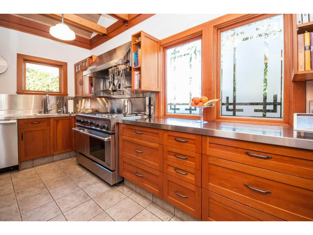 Bright kitchen with wooden cabinets, stainless steel countertops, and a view of greenery outside. - 1015 West 16th Ave, Vancouver West Side