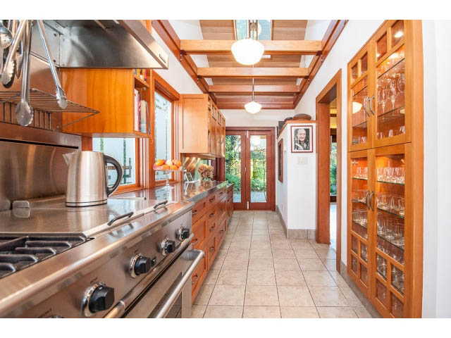 Bright kitchen with stainless steel appliances, wooden cabinets, and tiled floor. - 1015 West 16th Ave, Vancouver West Side