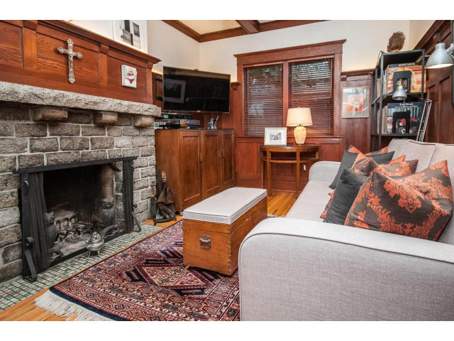 Cozy living room with stone fireplace, hardwood floors, and patterned rug. - 1015 West 16th Ave, Vancouver West Side