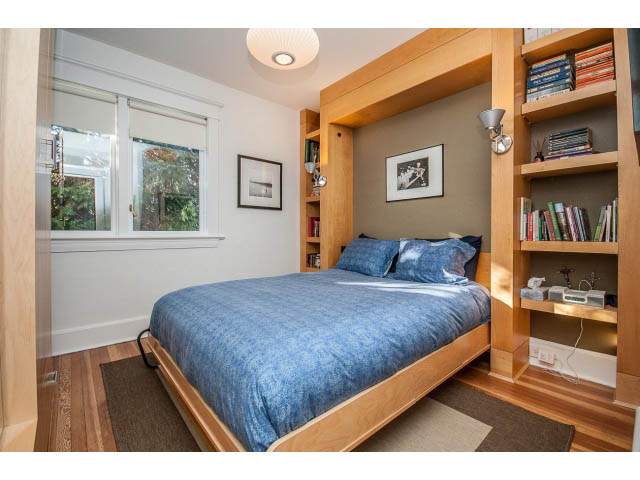 Bright bedroom with built-in shelves, hardwood floors, and a window view. - 1015 West 16th Ave, Vancouver West Side