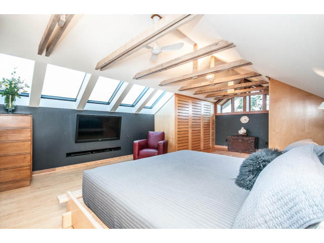 Spacious attic bedroom with skylights, exposed beams, and a cozy bed setup. - 1015 West 16th Ave, Vancouver West Side