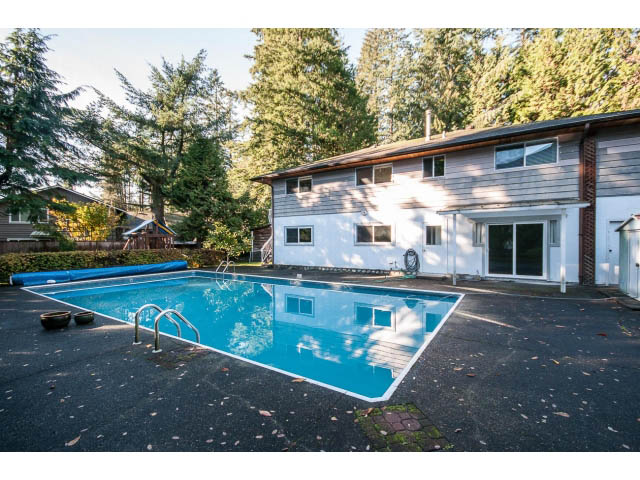 Spacious living room with large sliding glass doors and a pool area. - 3888 Capilano Rd, North Vancouver
