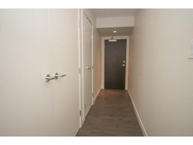 Bright hallway with white walls and dark wooden flooring leading to a door at the end. - 805 - 1009 Harwood Street, Vancouver Downtown
