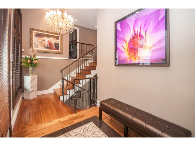 Foyer with hardwood floors, staircase, chandelier, and large flower artwork. - 3765 Dollarton Hwy, North Vancouver