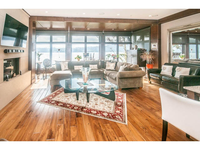 Spacious living room with hardwood floors, large windows, and a cozy fireplace. - 3765 Dollarton Hwy, North Vancouver