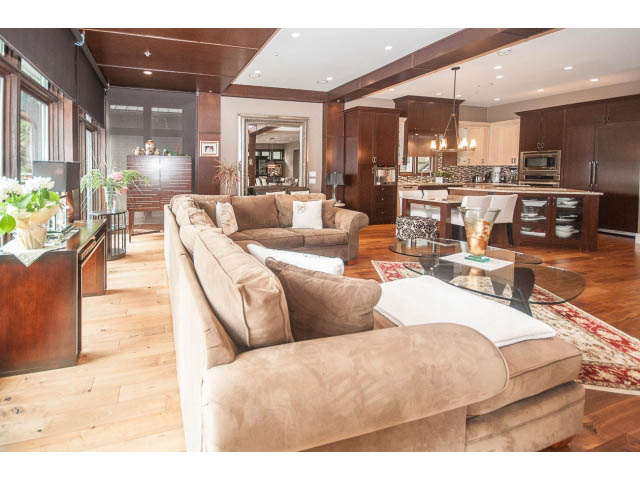Spacious living room with hardwood floors, large windows, and a cozy sofa. - 3765 Dollarton Hwy, North Vancouver