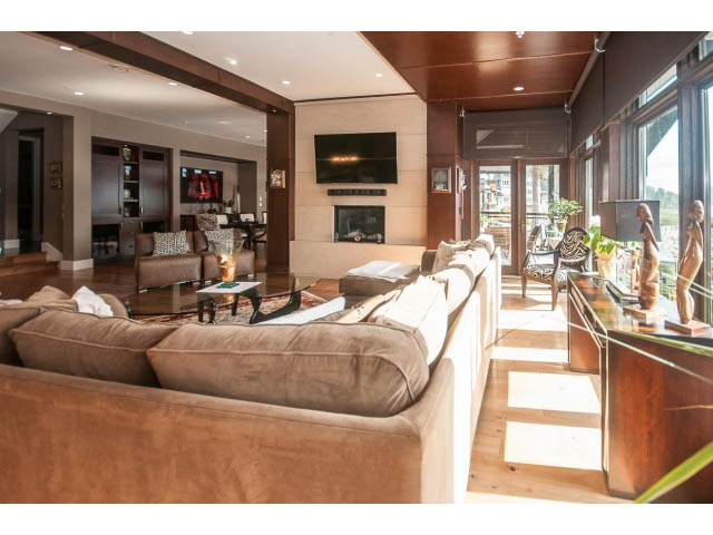 Spacious living room with large windows, hardwood floors, and a cozy fireplace. - 3765 Dollarton Hwy, North Vancouver