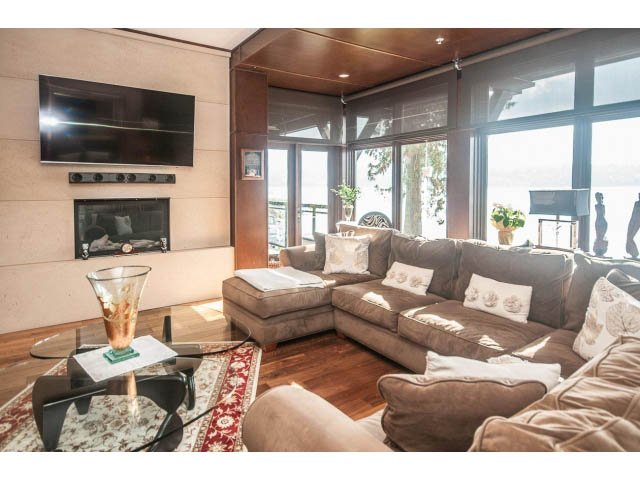 Spacious living room with large windows, hardwood floors, and a cozy fireplace. - 3765 Dollarton Hwy, North Vancouver