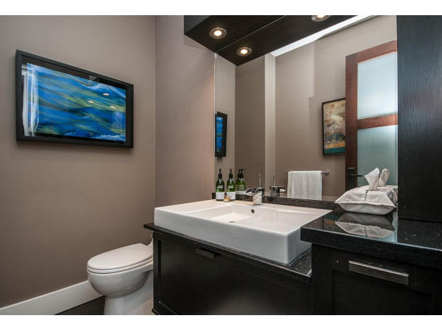 Modern bathroom with sleek black countertops and a large mirror. - 3765 Dollarton Hwy, North Vancouver
