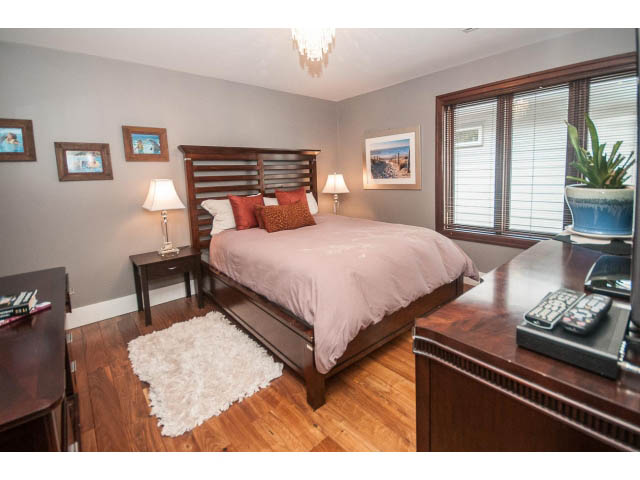 Furnished bedroom with hardwood floors, wooden headboard, and a cozy rug. - 3765 Dollarton Hwy, North Vancouver