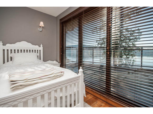 Bright bedroom with wooden blinds and a view of the water. - 3765 Dollarton Hwy, North Vancouver
