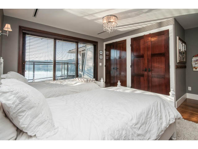 Spacious bedroom with large windows, city view, and wooden closet doors. - 3765 Dollarton Hwy, North Vancouver