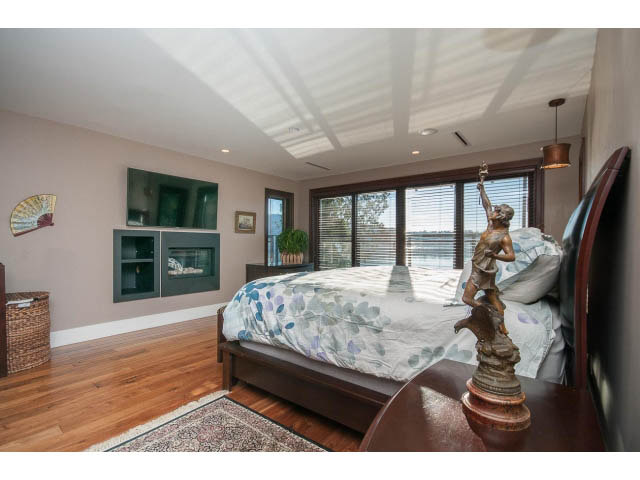 Spacious bedroom with hardwood floors, large windows, and a cozy fireplace. - 3765 Dollarton Hwy, North Vancouver