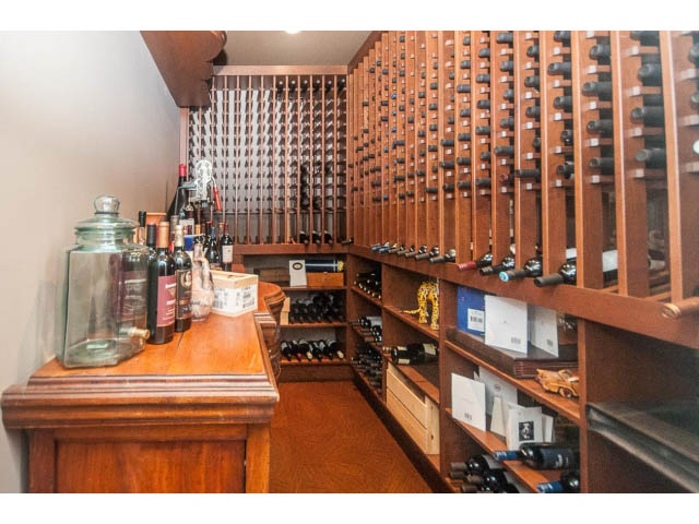 Wine cellar with wooden shelves and glass jars, hardwood floors. - 3765 Dollarton Hwy, North Vancouver