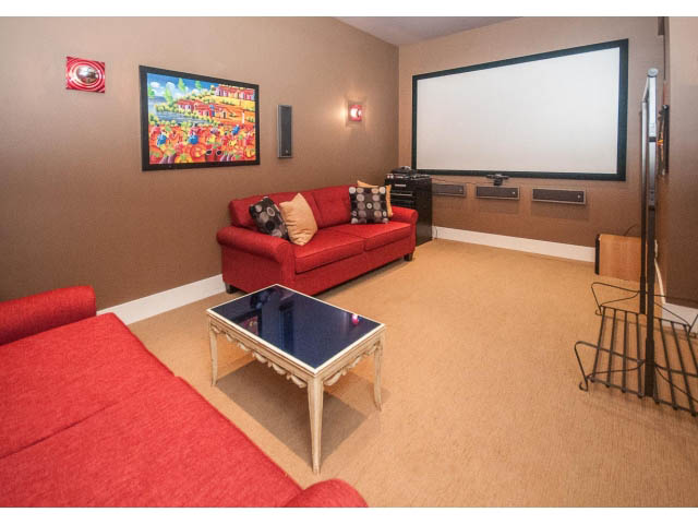 Bright living room with red couch, large projection screen, and vibrant artwork. - 3765 Dollarton Hwy, North Vancouver