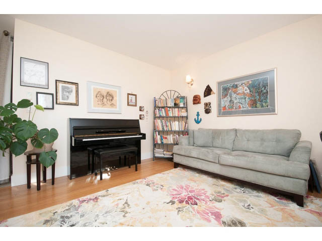 Furnished living room with a piano, bookshelf, and floral rug. - 3765 Dollarton Hwy, North Vancouver