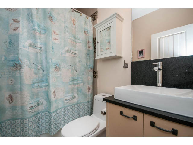 Bathroom with black countertops and light wood cabinets. - 3765 Dollarton Hwy, North Vancouver
