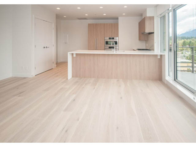 Bright kitchen with white countertops and hardwood floors, offering a city view. - 510 - 2738 Library Lane, North Vancouver