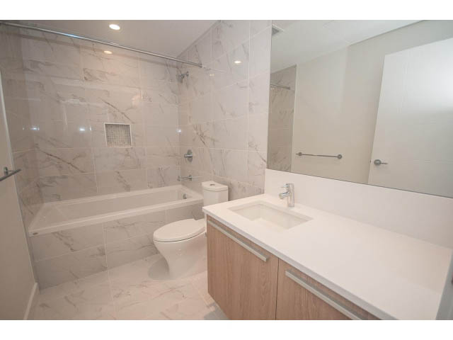 Modern bathroom with marble tiles and a large vanity counter. - 510 - 2738 Library Lane, North Vancouver