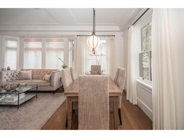 Bright living room with hardwood floors and large windows, showcasing a cozy sofa and dining area. - 1973 W 15th Ave, Vancouver West Side