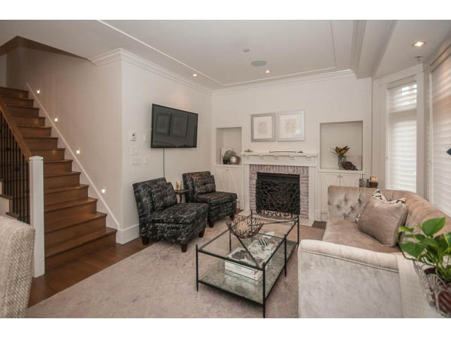Spacious living room with plush furniture, fireplace, and large TV. - 1973 W 15th Ave, Vancouver West Side