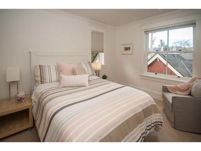 Spacious bedroom with striped bedding and city view. - 1973 W 15th Ave, Vancouver West Side