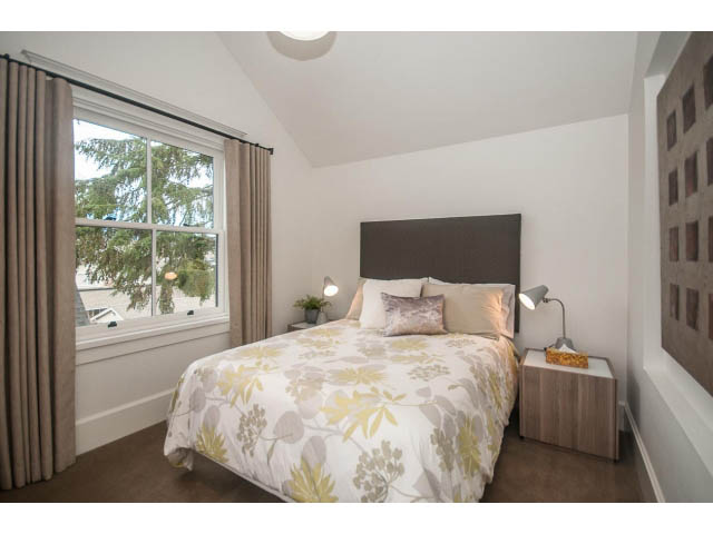 Spacious bedroom with floral bedding and large window, modern decor. - 1973 W 15th Ave, Vancouver West Side