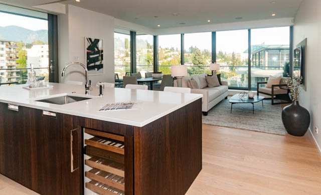 Bright kitchen with modern white countertops and hardwood floors, showcasing a city view. - 601 - 1355 Bellevue Ave, West Vancouver