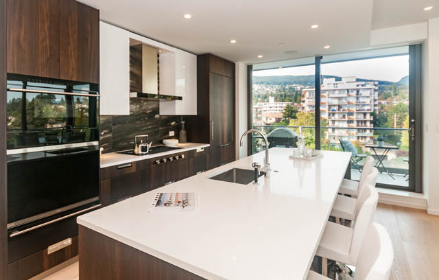 Bright kitchen with modern black and white cabinets, city view, and hardwood floors. - 601 - 1355 Bellevue Ave, West Vancouver