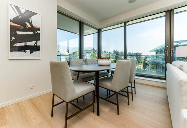 Bright dining area with large windows, hardwood floors, and a city view. - 601 - 1355 Bellevue Ave, West Vancouver