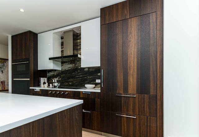 Bright kitchen with dark wood cabinets, white countertops, and modern appliances. - 601 - 1355 Bellevue Ave, West Vancouver
