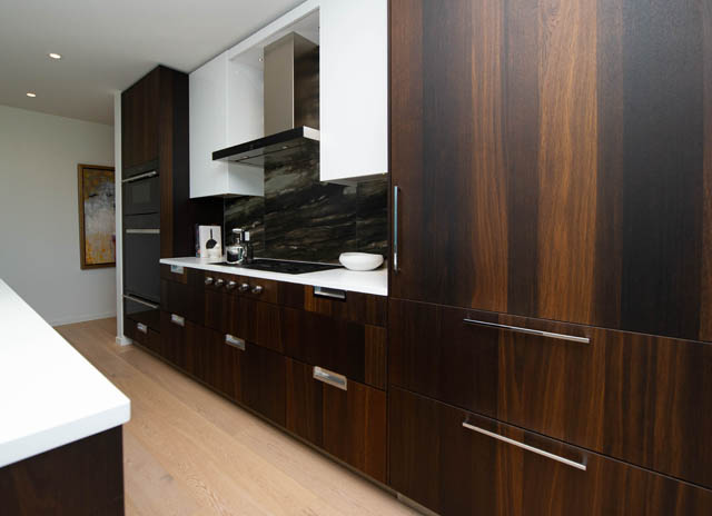 Modern kitchen with dark wood cabinets, white countertops, and hardwood floors. - 601 - 1355 Bellevue Ave, West Vancouver