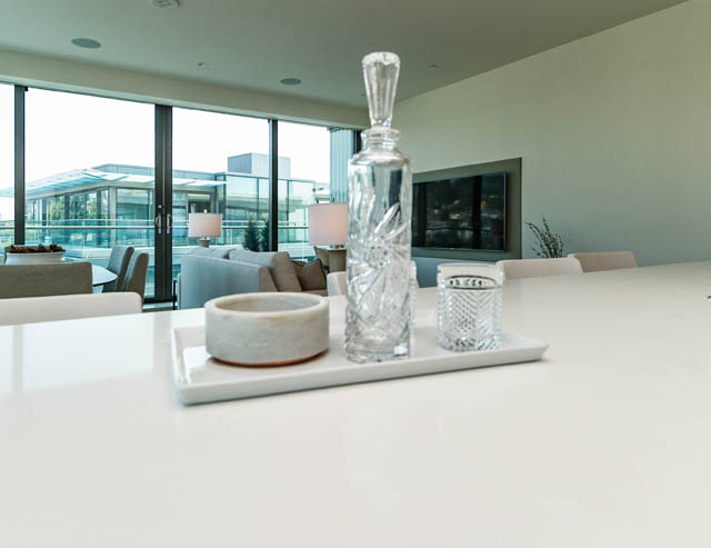Bright living room with white countertops and modern decor, city view through large windows. - 601 - 1355 Bellevue Ave, West Vancouver
