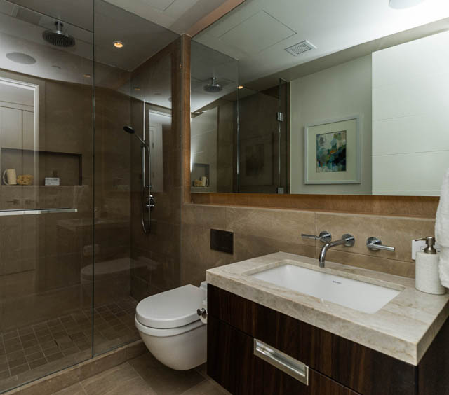 Modern bathroom with a sleek sink, dark wood cabinets, and a glass-enclosed shower. - 601 - 1355 Bellevue Ave, West Vancouver