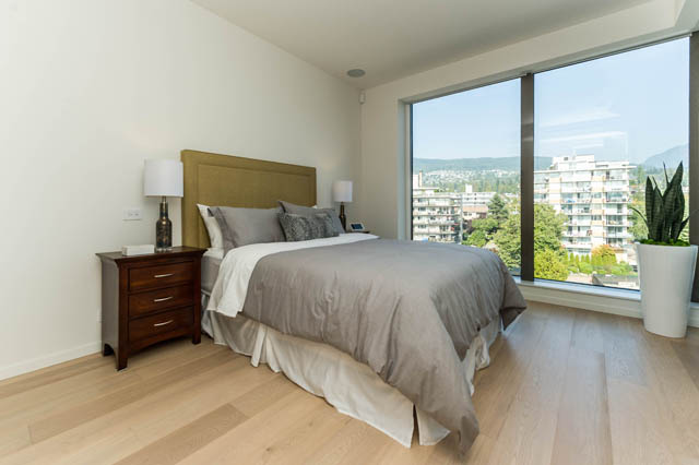 Spacious bedroom with hardwood floors, city view, and modern furnishings. - 601 - 1355 Bellevue Ave, West Vancouver
